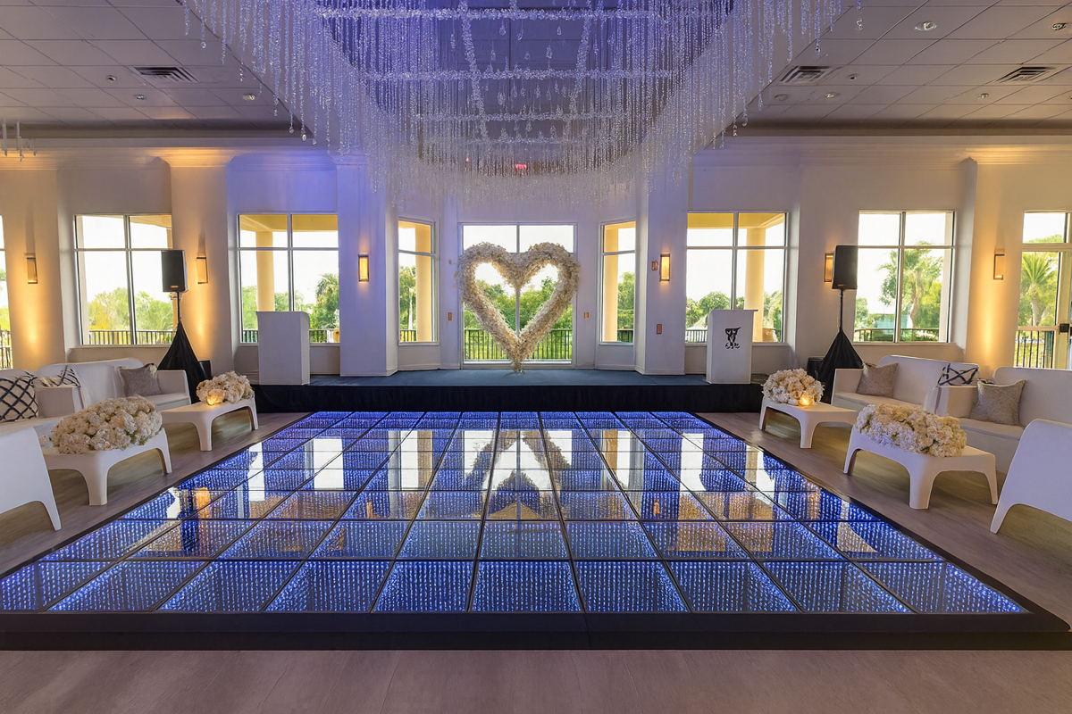 Elegant ballroom reception at night with candlelight glow, round tables with floral centerpieces and gold chairs