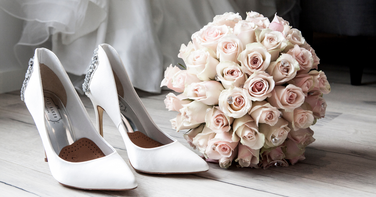 A pair of white heels next to a bridal bouquet.