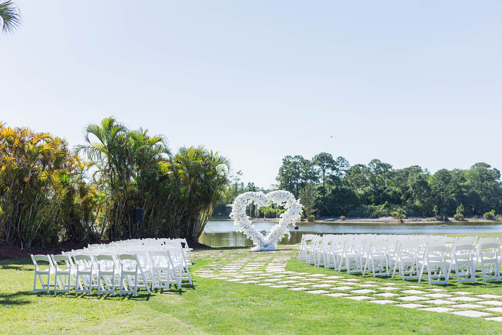 Palm Beach Florida wedding venue ceremony chairs, heart shaped arch with luxury flowers and waterfront views at a country club wedding venue in Southern Florida